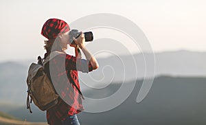 Woman tourist photographer with camera on top of mountain at sun
