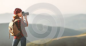 Woman tourist photographer with camera on top of mountain at sun