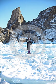 Woman tourist photographer ioutdoors, standing at frozen surface of lake Baikal photo