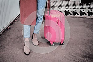Woman tourist with pink suitcase waiting the train at train station background. travel, tourist, vacation concept.