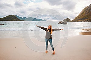 Woman tourist raised hands enjoying ocean view walking on sandy Haukland beach travel in Norway active vacations outdoor