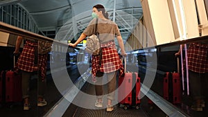Woman tourist with a red luggage on an moving walkway or escalator at the international airport. Traveler with suitcase