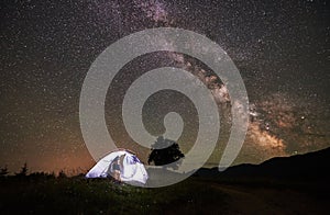 Woman tourist resting at night camping under starry sky and Milky way