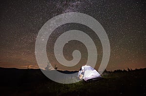 Woman tourist resting at night camping under starry sky and Milky way