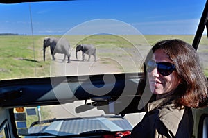 Woman tourist on safari in Africa, car travel in Kenya, elephants in savanna