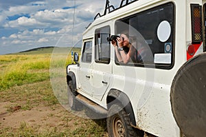 Woman tourist on safari in Africa, travel in Kenya, watching wildlife in savanna with binoculars