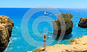 Woman tourist standing with arms raised in Algarve coast