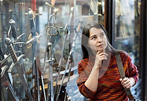 Woman tourist, standing near the window of a souvenir shop, examines the goods