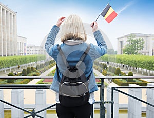 Woman tourist stands with the flag of Belgium against the background of the Mount of the Arts in Brussels, Belgium