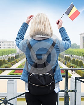 Woman tourist stands with the flag of Belgium against the background of the Mount of the Arts in Brussels, Belgium