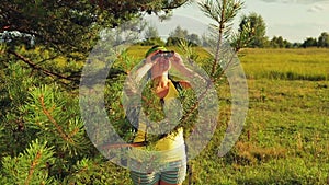 A woman tourist stands in a forest glade and looks through binoculars where to go next.