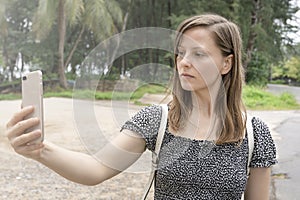 A woman tourist takes a selfie against the backdrop of palm trees and sand. Vacation and tourism, recreation.