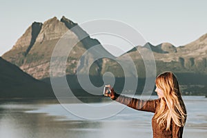 Woman tourist taking selfie by smartphone Travel Lifestyle concept adventure vacations outdoor Norway sunset mountains and sea