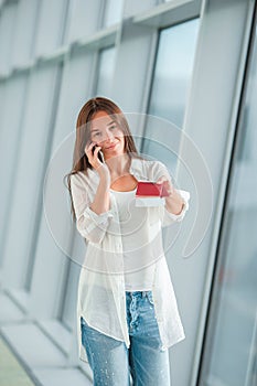 Woman tourist talking by cell phone with boarding passport at airport