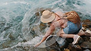 Woman tourist touch clear cool water from a mountain river