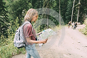 A woman on a tourist trail with a backpack holds a map.