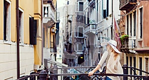 Woman tourist travel in Italy. Young girl with a white hat in venice on an old street. Girl traveling to Venice