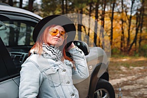 Woman tourist travel yellow classic polarized sunglasses by SUV car for road trip in autumn. Traveler parking the car and enjoy