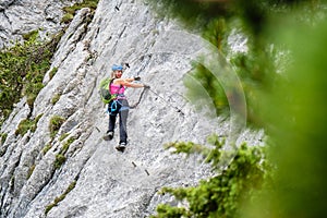 Woman tourist on a traverse at Intersport Klettersteig Donnerkogel via ferrata route, near Gosau, in Austria.