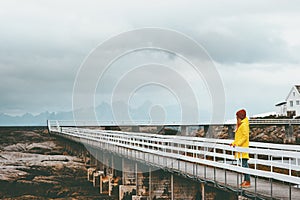 Woman tourist walking alone on bridge Travel Lifestyle emotional concept vacations outdoor yellow raincoat clothing foggy mountain