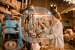 Woman tourist walking in Arab market near Al Seef with crockery, lamps and lanterns in the old style