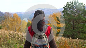 Woman tourist walking in fall forest on sunny autumn day. Hiker traveler woman hikking on mountain, enjoying panoramic