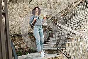 Woman tourist walking on the street in european old city using map