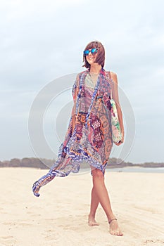 Woman tourist walking on a tropical summer vacation beach wearing sunglasses and beach bag relaxing on travel holidays