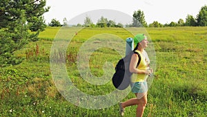 A woman tourist walks through a forest glade and looks through binoculars where to go next.