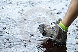 Woman in tourist waterproof hiking boots walking on water in puddles in the rain