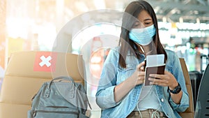 Woman tourist wearing protective mask using smart phone in airport terminal