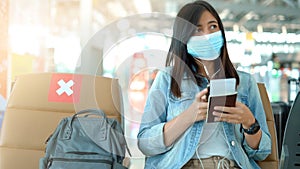 Woman tourist wearing protective mask using smart phone in airport terminal