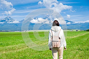 A woman tourist in a white hoodie and a backpack enjoys a beautiful view of the Tatra mountains while standing in a