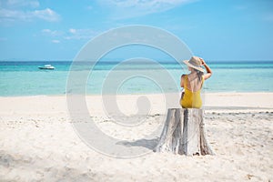 Woman tourist in yellow swimsuit and hat, solo traveller looking beautiful sea view at bamboo island on Phi Phi don island, Krabi