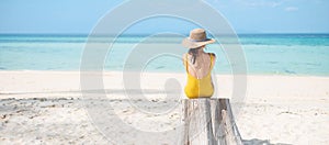 Woman tourist in yellow swimsuit and hat, solo traveller looking beautiful sea view at bamboo island on Phi Phi don island, Krabi