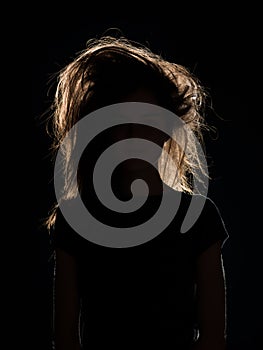 Woman with tousled hair in black shadow