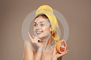 woman with a towel on her head clean skin grapefruit in hand cropped view