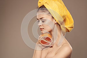 woman with a towel on her head clean skin grapefruit in hand cropped view