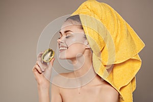 woman with a towel on her head with fruit kiwi in hand cropped view