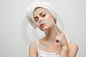 woman with a towel on her head on a light background and pimples on her face transitional age clean skin model