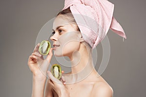 woman with a towel on her head after shower kiwi in hand cropped view