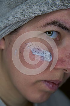 Woman with a towel over your head and smear of scrab on her face.