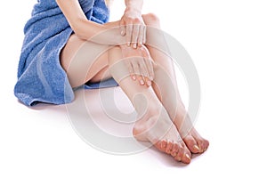 Woman in towel sitting on floor, stroking her legs