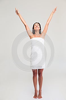 Woman in towel standing with raised hands up