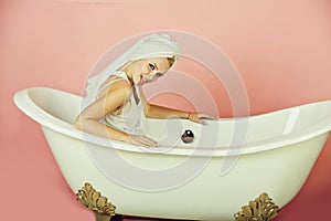 Woman with towel turban sitting in white bathtub