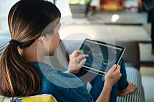 Woman Trading Online Using Tablet Computer On Sofa