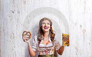 Woman in traditional bavarian dress holding beer and pretzel