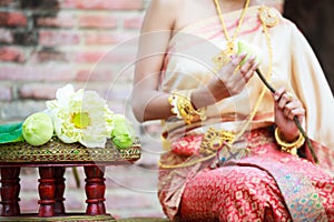 Woman in traditional clothes fold lotus flower petals used in rituals of Buddhism religion. A Lotus represents purity of body
