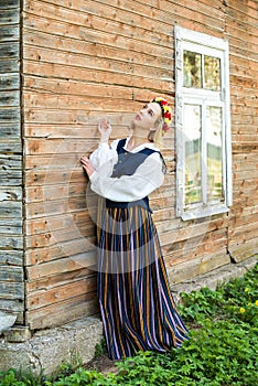 Woman in traditional clothing posing on nature in village.