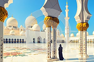 Woman in traditional dress inside Sheikh Zayed Mosque â€“ tourist wearing black abaya visiting famous arabian religious temple